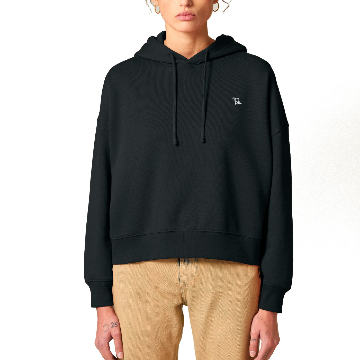 Schwarzer Damen Hoodie mit dezentem weißen Logo auf der Brust, kombiniert mit einer beigefarbenen Hose.