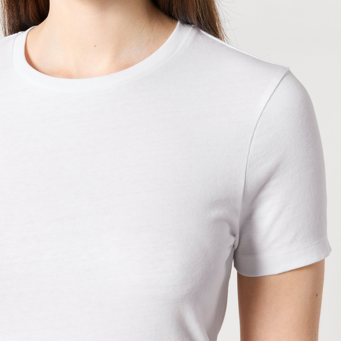 Nahaufnahme eines weißen T-Shirts mit kurzen Ärmeln und Rundhalsausschnitt, gefertigt aus umweltfreundlicher Bio-Baumwolle. Perfekt für minimalistische basic Mode-Looks.