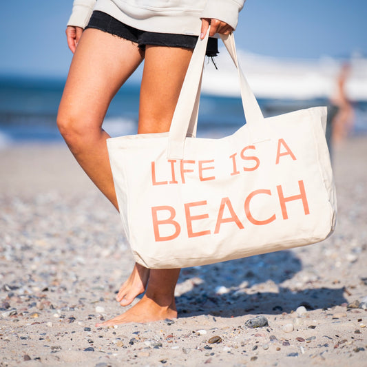 Frau trägt große Canvas Tasche mit rotem pinken Print am Strand
