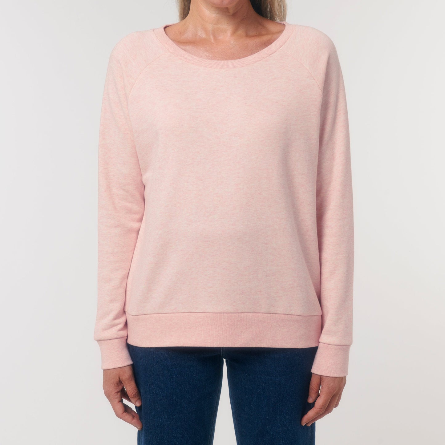 Damen-Sweatshirt in zartem Rosa mit Raglanärmeln und Rundhalsausschnitt, locker sitzend und aus weichem Stoff, kombiniert mit schlichten blauen Jeans.