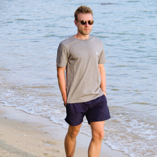Unisex Bio Baumwoll T-Shirt als Strandmode. Getragen von einem blonden Mann am Meer bei der Abendsonne.