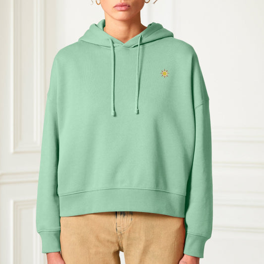 Damen Hoodie in mintgrün mit gestickter Sonne auf der Brust in ca. 3x3 cm kombiniert mit einer beigen Hose.