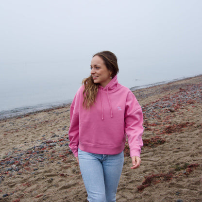 Rosa bzw. Pink Hoodie am Strand, kombiniert mit hellblauer Jeans, Teil der nachhaltigen Kollektion auf fimpa.de.