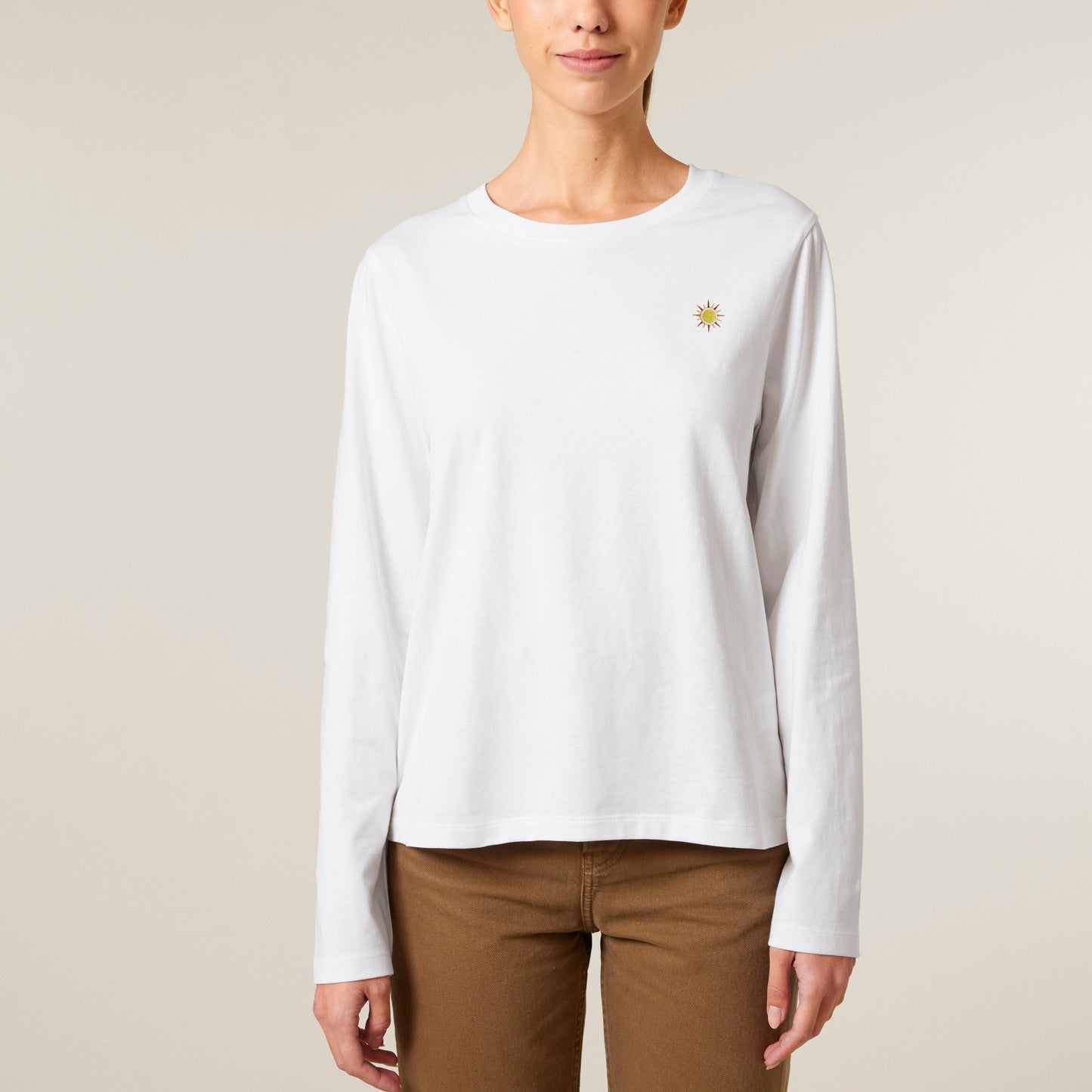 Long Sleeve 100 % Bio-Baumwolle mit gesticktem Sonnen-Motiv und mit brauner Hose kombiniert.
