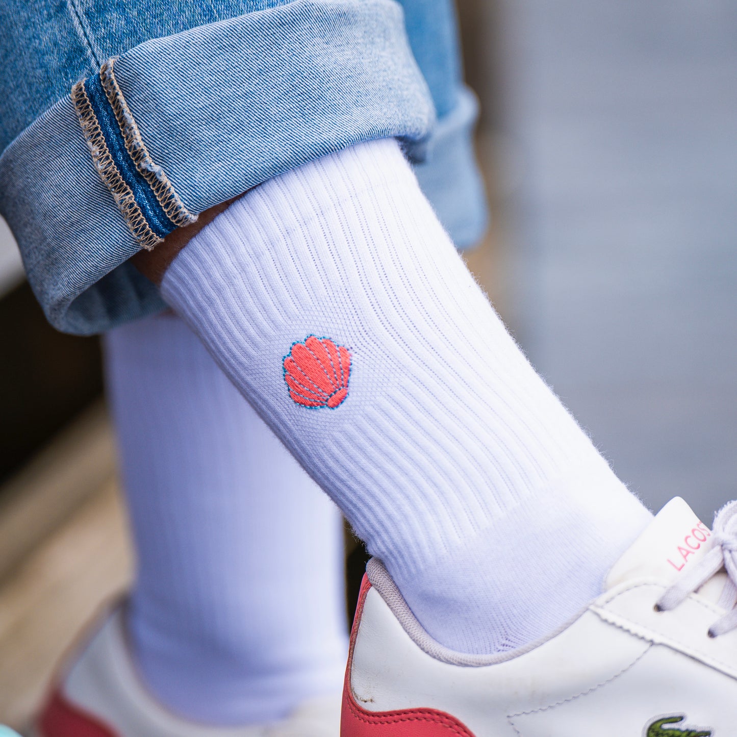Weiße Tennissocke mit blau grell rot gesticktem Muschel-Motiv.